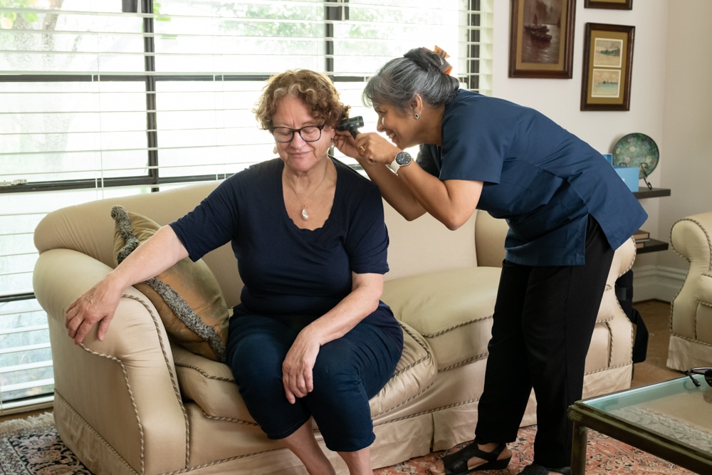 GP examining a patient at home as part of regular care